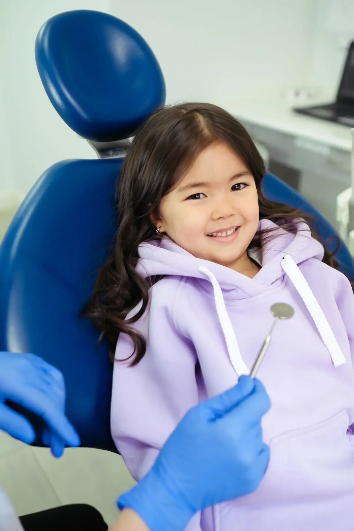 Menina sorrindo na cadeira do dentista durante a consulta